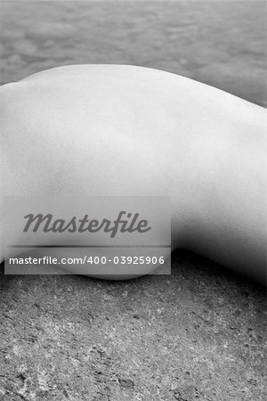 Abstract close up of young Asian female nude lying on rock.