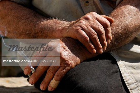 Image shows the hands of a hard working man as he enjoys his cigarette