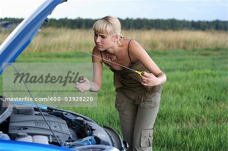 young blond woman with her broken car. The girl is sad