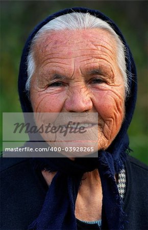 Image shows a portrait of an old Greek happy lady, wearing a scarf and smiling to the camera