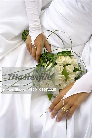 Bride holding her wedding bouquet against her dress
