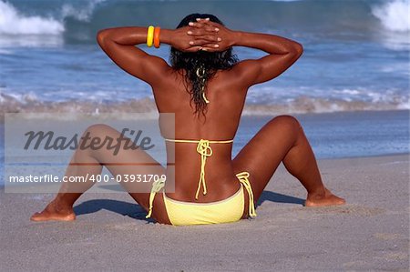 African-American female taking sunbath on beach by ocean