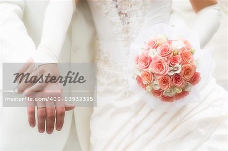 just married - young couple in wedding wear with bouquet of roses. Soft-focused image in high key