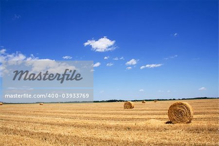 Wide open stubble field with straw or hay bales under a spectacular summer sky