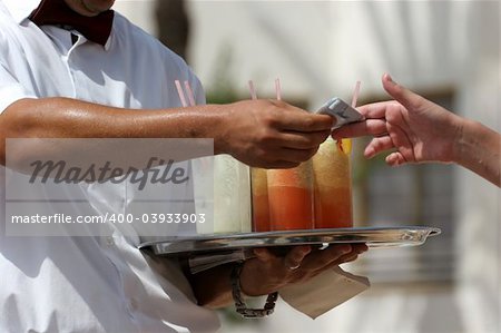 Waiter handling a salver with colorful cocktails.