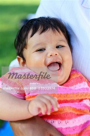 Closeup of a very cute baby or toddler in bright pink clothings laughing.