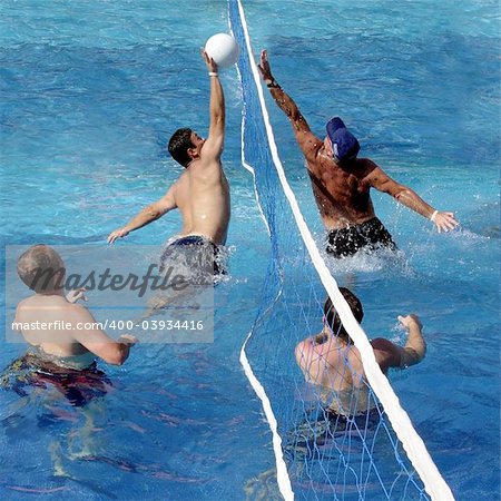 4 men playing water polo in a swimming pool