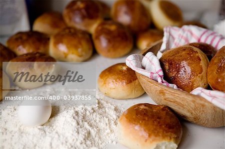 Close up detail of freshly baked hot cross buns and a few ingredients in romantic renaissance lighting and a shallow depth of field.