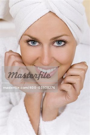 Close up portrait of a beautiful and happy young woman in a bath robe and towel