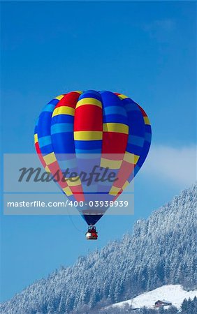 A hot-air balloon flying over a chalet in the Swiss alps.