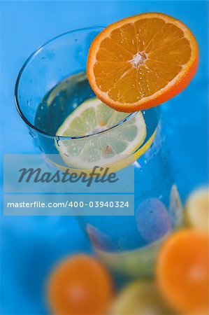 oranges and lemons in transparent glass over blue background