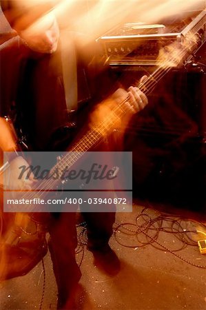 Blurry atmospheric abstract noisy hazy image of a bass player rippin' thru songs. Shot with slow shutter speed and flash for lots of movement and effect.