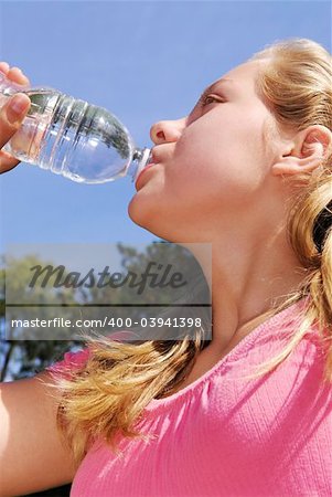 Young girl drinking water out of a plastic bottle outside