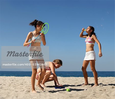 Three teen girls playing with bubbles on the beach