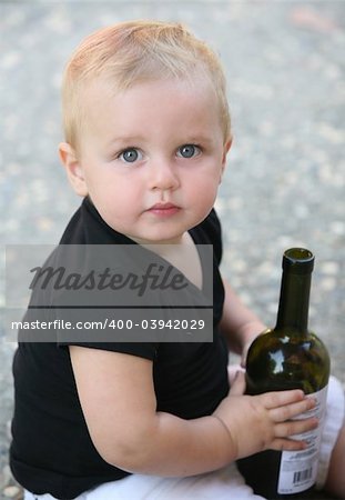 Baby boy holding a bottle of wine