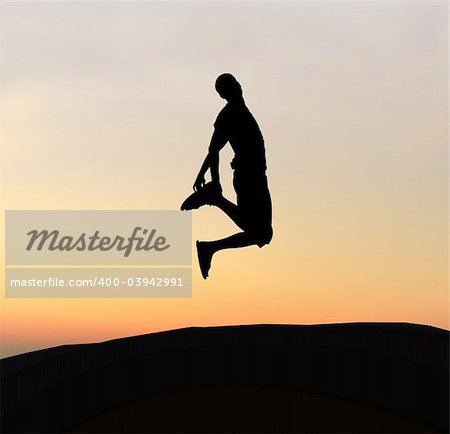 Young boy silhouette jumping of joy - sunset background