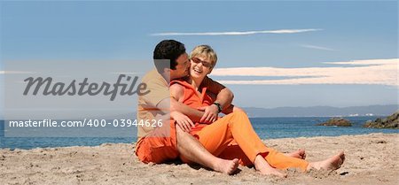 Happy couple in orange clothes on the beach