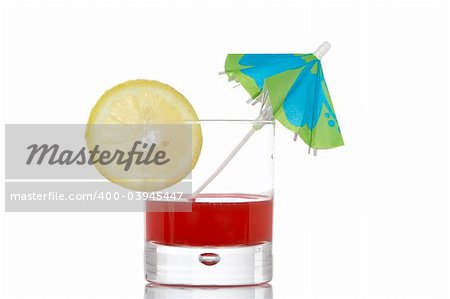 A glass of red juice with a lemon slice and umbrella, reflected on white background