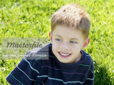 Little curious boy sitting on a grass
