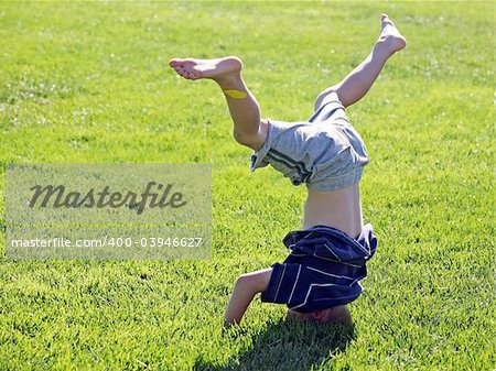 Little boy standing on his head on a grass