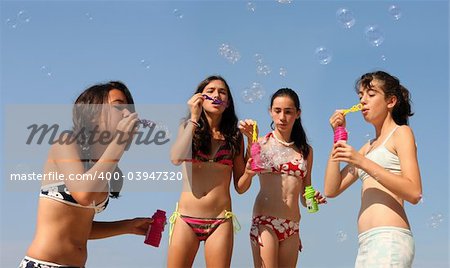 Four girls playing with bubbles on the beach