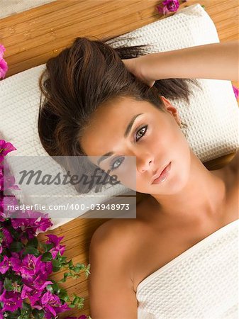 a nice portrait of a beautiful brunette laying down on a wood carpet and violet flower near