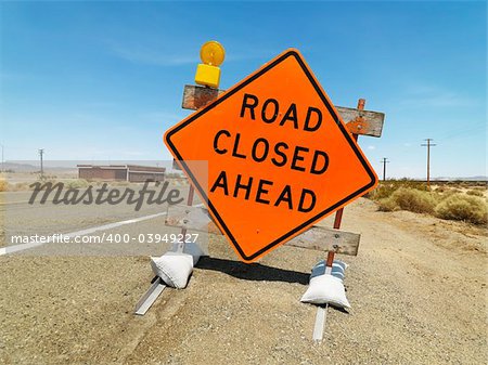 Road sign on rural highway warning that road is closed ahead.