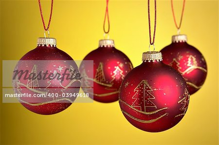 Christmas baubles hanging over yellow background