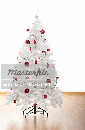 Christmas white tree with red ornaments in a house