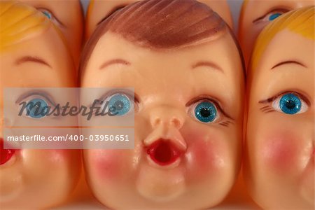 A close up of plastic doll faces ready for assembly into toys