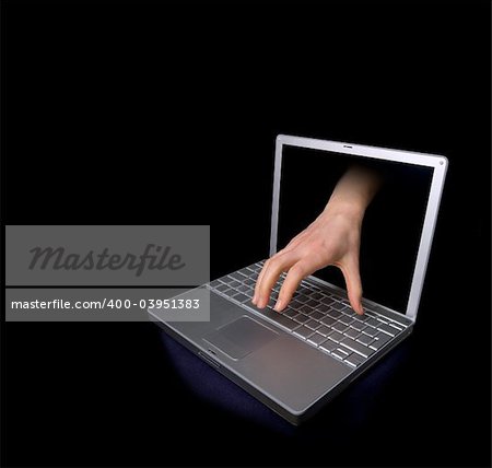 A hacker concept image of a hand coming through the computer.