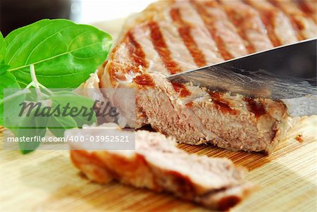 Grilled steak being cut on a cutting board, closeup