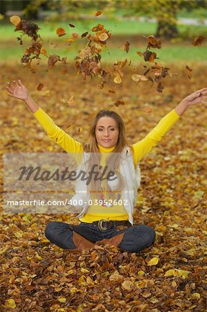 20-25 years old beautiful sexy woman portrait playing with leafs in natural autumn outdoors