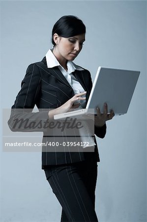 Beautiful and sexy brunette business woman with laptop computer. She is isolated on clear background
