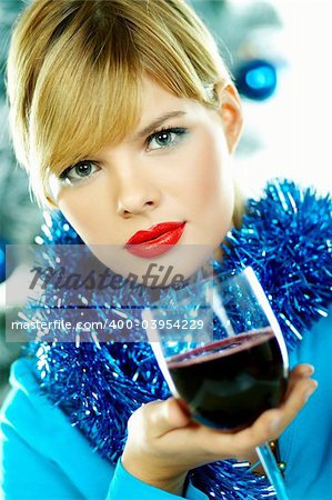 Beautiful young woman holding glass of red wine next to christmas tree on white background