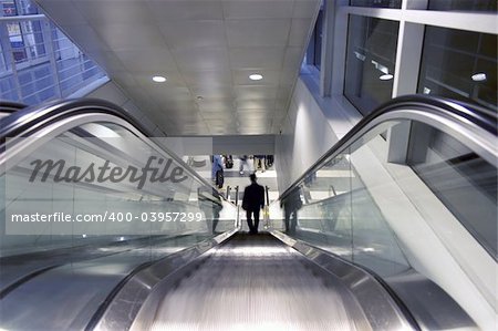 This is a 1 point perspective of a business guy traveling down an escalator.