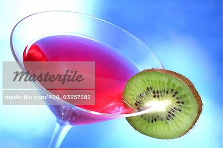 Red cocktail with kiwi garnish and blue light background