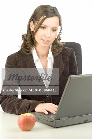 Young woman typing on a laptop with an apple on the desk