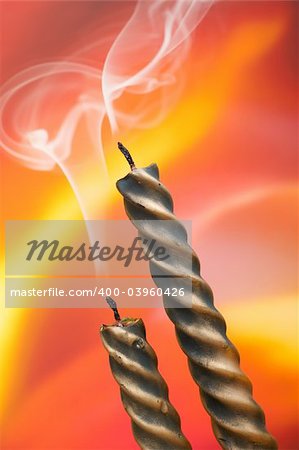 Two candles and smoke over color background. Shallow DOF