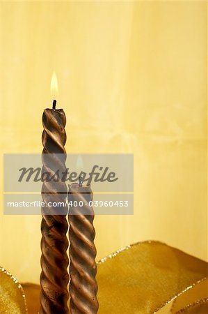 Two christmas candles over yellow background, vertical composition. Shallow DOF