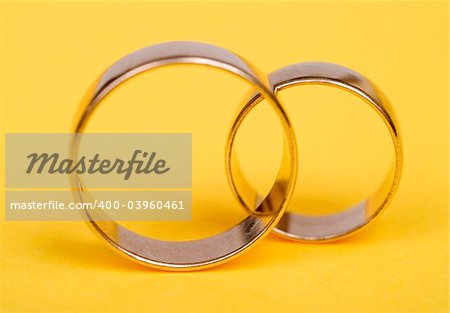 Gold wedding rings on yellow light bacground