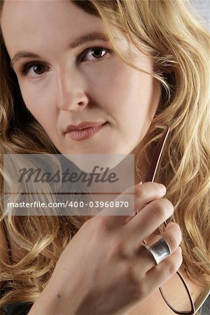 an attractive woman with long hair chews the handle of glasses