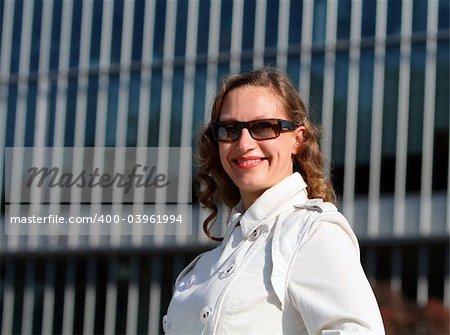 Business woman standing in front of an office building and smiling.