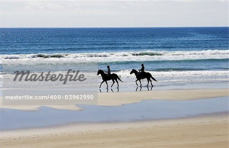 People on the beach riding horses.