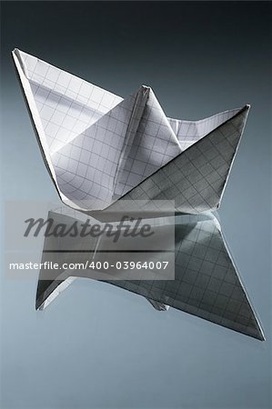 White paper ship and its reflection on a mirror