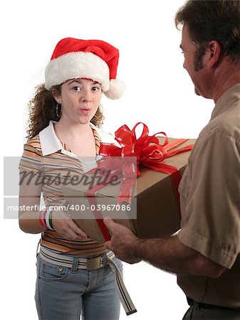 a surprised girl in a santa hat receiving a christmas gift from a delivery man - isolated