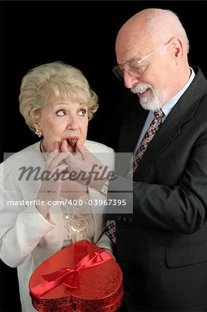 A humorous picture of a husband feeding his wife Valentine candy.  She doesn't look too sure about it.  Black background