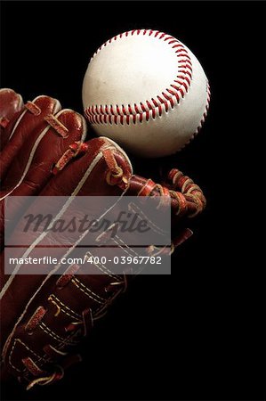 Close up of a baseball glove and a ball on a black background