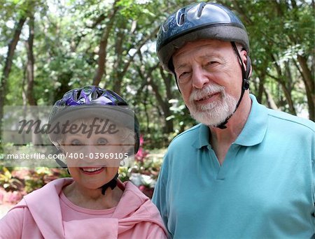 An attractive senior couple wearing bike helmets.