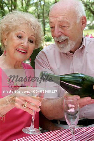 A handsome senior husband pouring champagne for his beautiful wife.